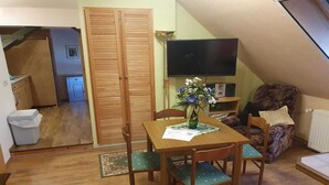 A cozy room with a wooden dining table, chairs, a TV, and a sofa. - Ferienwohnung im Luckaitztal Gosda (Luckaitztal)