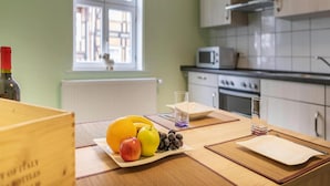 A kitchen with a dining table set for two, featuring a plate of fruit, a bottle of wine, and a glass. - Ferienwohnung Schlossblick, Wernigerode (Wernigerode)