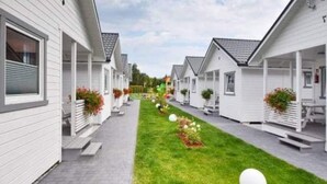 En rad vita, flyttbara hus med tillhörande verandor, en asfalterad gångväg och en välskött gräsmatta.