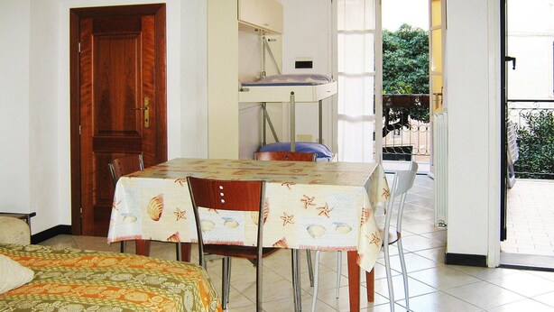 A room with a bed, a table with chairs, a bunk bed, and a door. - Apartment in Mongelia (Moneglia)