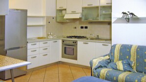 A compact kitchen with a refrigerator, stove, oven, and a dining table. - Apartment in Mongelia (Moneglia)