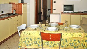 A dining area with a table set for four, a kitchen with a stove and cabinets, and a television on a stand. - Apartment in Mongelia (Moneglia)