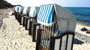 A row of beach chairs with striped canopies on a sandy beach.