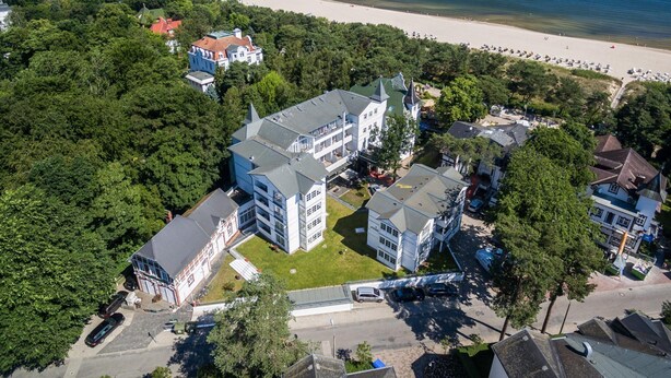 An aerial view of a coastal area with a large building complex, a beach, and a pier.