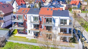 A modern multi-story residential building with large windows and balconies, surrounded by a residential area with similar architecture.