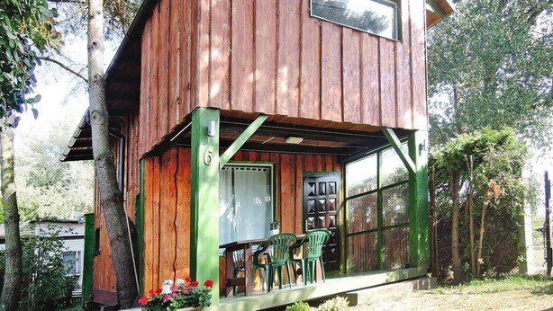A wooden cabin with a porch, a window, and a door. - Holiday Home in Sulomino With Private Beach (gmina Wolin)
