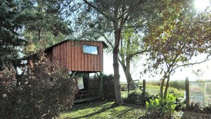 A rustic wooden cabin with a small deck, surrounded by trees and a fence. - Holiday Home in Sulomino With Private Beach (gmina Wolin)