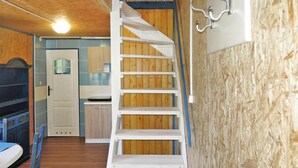 A staircase leading to a loft bedroom with a bunk bed and a kitchen area in the background. - Holiday Home in Sulomino With Private Beach (gmina Wolin)