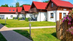 Une rangée de cabanes aux toits rouges, un espace d’accueil et un chemin pavé.