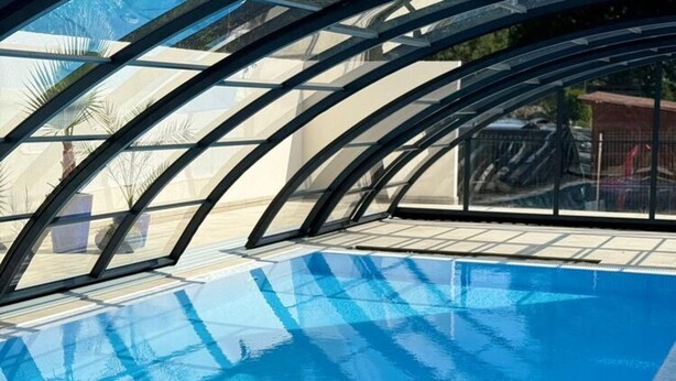 Une piscine dotée d’une structure de toit en verre.