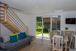 A modern living room with a grey sofa, wooden staircase, and a dining area with a table and chairs. - Comfortable, Two-story Holiday Home, Summer Pool (Postomino)