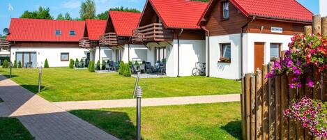 A row of modern, red-roofed cabins with a paved walkway leading to the entrance.