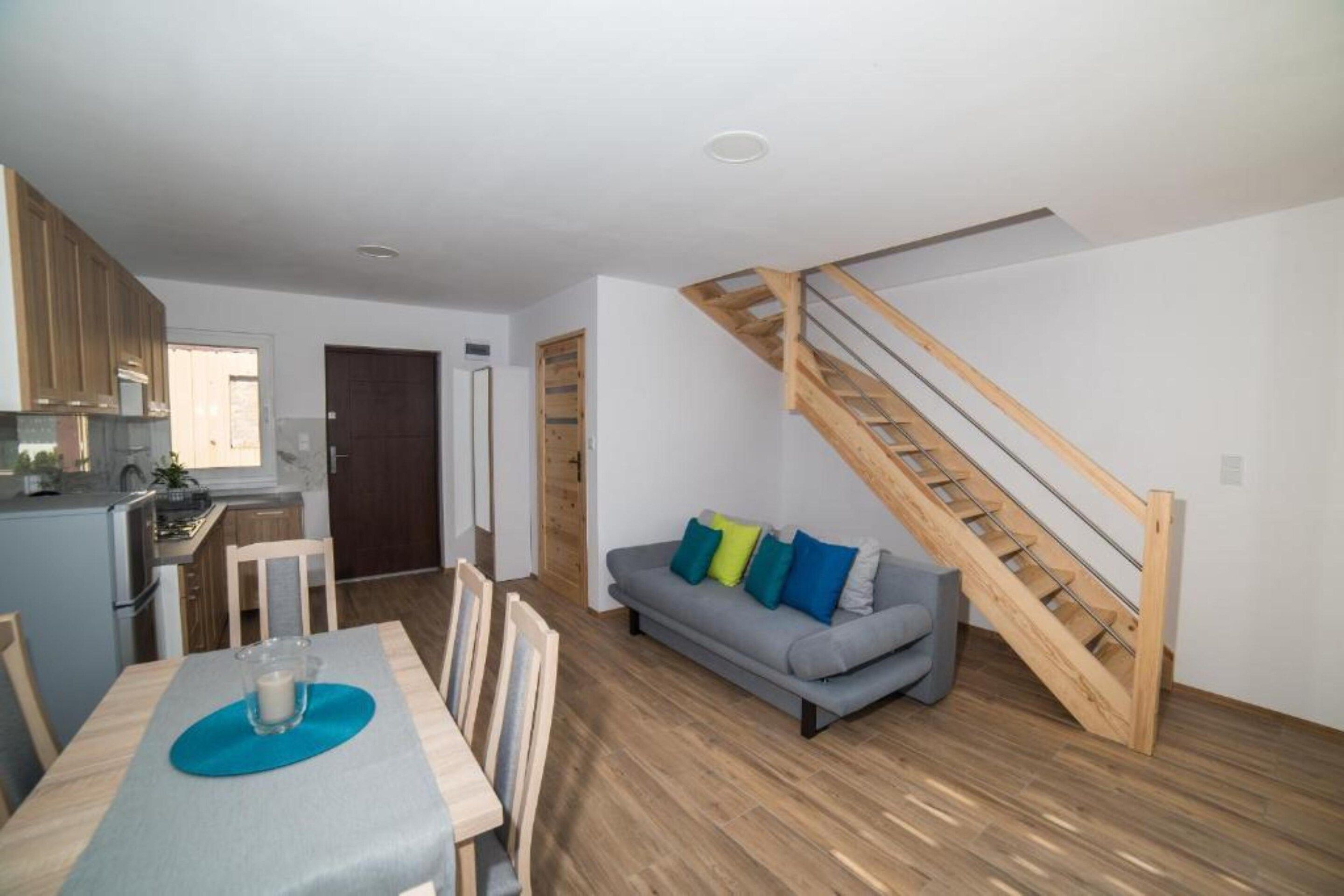 Een modern interieur met een eethoek, een bank en een houten trap.