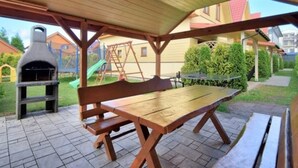 An outdoor patio with a wooden table and benches, a barbecue grill, and a swing set. - Holiday Studio Near the Beach, Playground (Mielno)