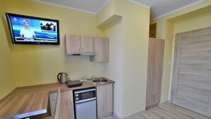 A compact kitchen with a built-in oven, a sink, and a television mounted on the wall. - Holiday Studio Near the Beach, Playground (Mielno)