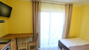 A room with a bed, a desk with a chair, a television, and a window with curtains. - Holiday Studio Near the Beach, Playground (Mielno)