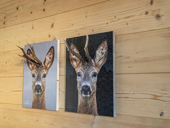 Deux tableaux représentant des cerfs, accrochés à un mur en bois.