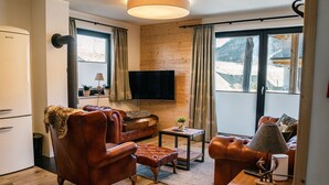 Un salon confortable avec un canapé, des fauteuils, une table basse et un téléviseur.