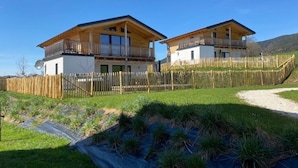 Un chalet à deux étages doté d’un balcon en bois et d’une cour clôturée.