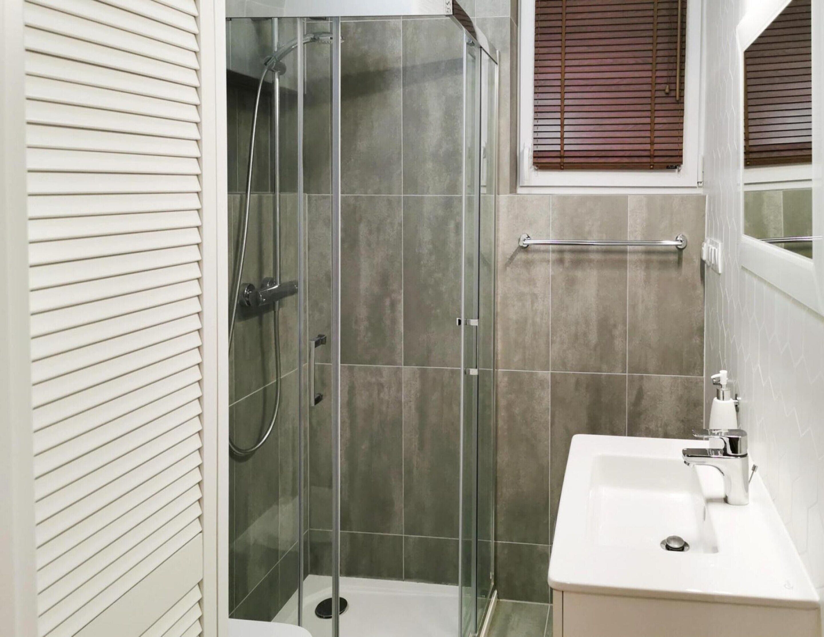 A bathroom with a glass-enclosed shower, a white sink, and a towel rack.