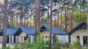 A row of cabins with a sloped roof, surrounded by a forested area. - Holiday Cottages Close to the Beach, Jaroslawiec (Postomino)