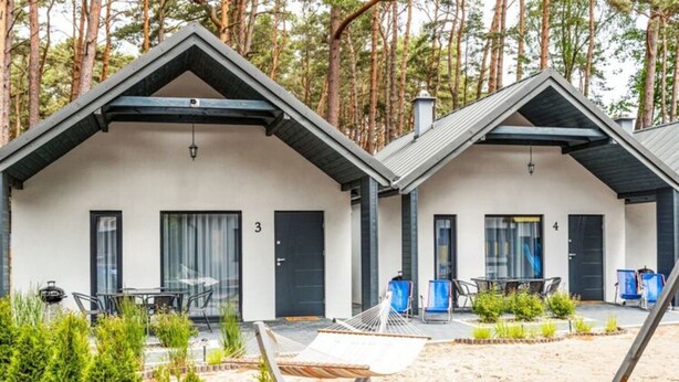 A modern cabin-style building with a covered patio, a hammock, and a small garden area. - Holiday Cottages Close to the Beach, Jaroslawiec (Postomino)