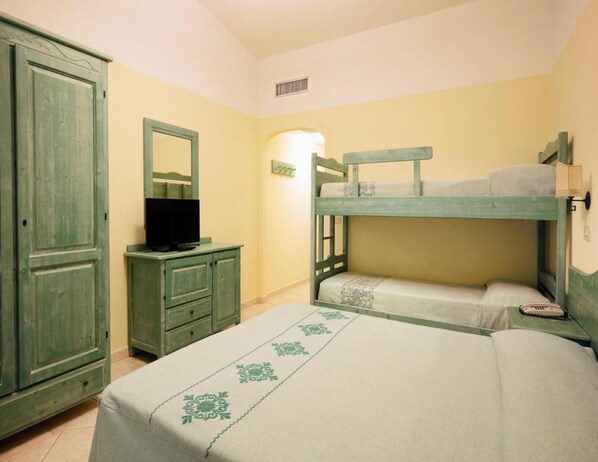 Une chambre avec des lits superposés, une commode, un téléviseur et un miroir.