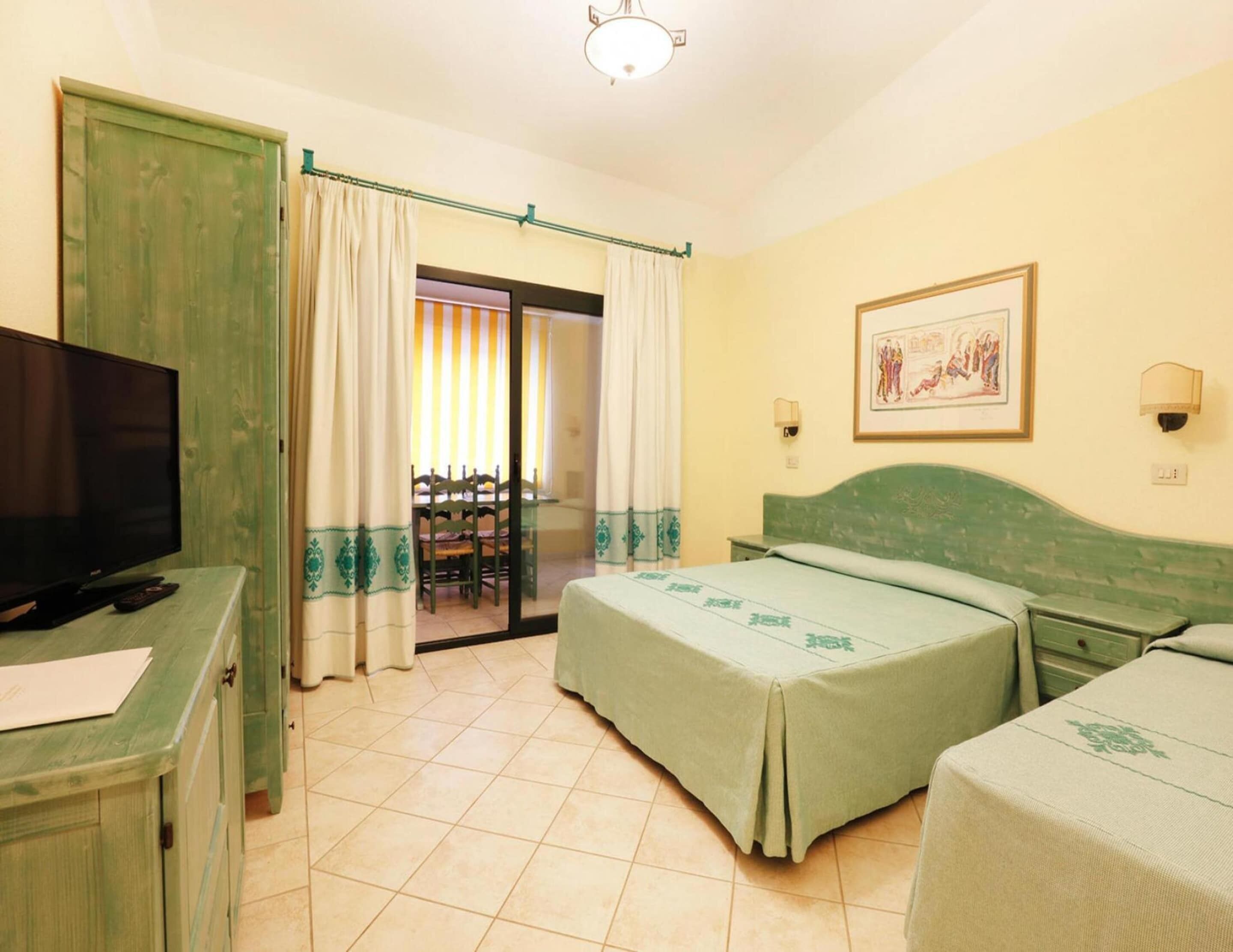 A hotel room with a bed, a TV, a desk, and a chair.
