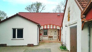 A two-story building with a red-tiled roof and a white facade. There is a visible garage door on the right side. - Ferienwohnung, Ribnitz-damgarten (Ribnitz-Damgarten)