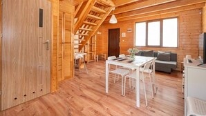 A wooden cabin interior with a dining area, a sofa, and a staircase. - Comfortable Holiday Cottages, Jaroslawiec (Postomino)
