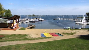 A marina with boats docked, a covered seating area, and a sandy beach. - Holiday Home by Lake Wilkasy With Rowboat (Gizycko)