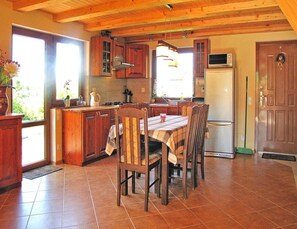 Eine Küche mit Holzausstattung, einem Esstisch mit Stühlen, einem Kühlschrank und einer Mikrowelle.