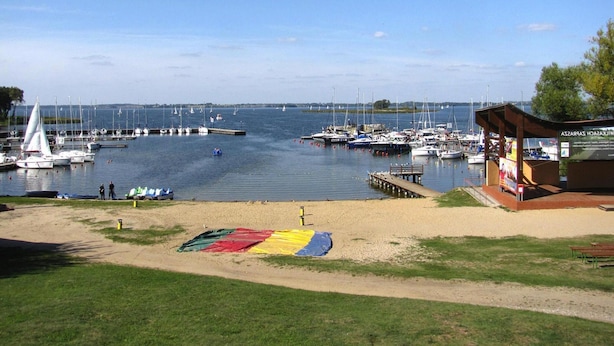A marina with boats docked, a sandy beach, and a small pavilion. - Holiday Home by Lake Wilkasy With Rowboat (Gizycko)