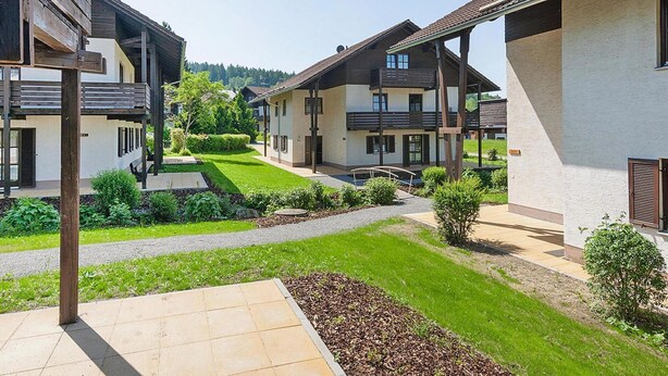 A residential area with modern houses, a well-maintained lawn, and a clear sky. - Ferienanlage Backerwiese in Neuschonau (Neuschoenau)