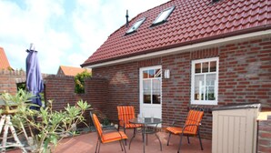 Un espace patio avec un mur en briques, une table et quatre chaises.