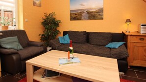 Un salon chaleureux avec une table basse en bois, un canapé, une plante en pot et un tableau accroché au mur.