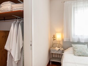 A neatly organized bedroom with a bed, a bedside table with a lamp, a nightstand, and a window with sheer curtains. - Apartment Beach Front, Arguineguin (Mogan)
