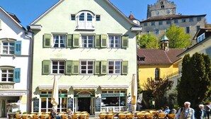 A building with a green facade, multiple windows with shutters, and outdoor seating. - Apartments Am Untertor, Meersburg (Meersburg)