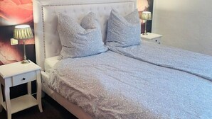 A bedroom with a tufted headboard, a patterned bedspread, and two bedside tables with lamps. - Apartments Am Untertor, Meersburg (Meersburg)