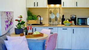 A modern kitchen with light wood cabinets, a microwave, a coffee maker, and a dining area with a table and chairs. - Spacious Holiday Home With a Terrace, Mielenko (Mielno)