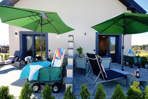 A patio area with outdoor seating, umbrellas, and a cart with a folded chair. - Spacious Holiday Home With a Terrace, Mielenko (Mielno)