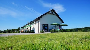 A white building with a sloped roof, green umbrellas, and a paved area in front. - Spacious Holiday Home With a Terrace, Mielenko (Mielno)