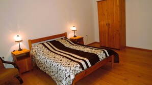 A bedroom with a wooden bed, two bedside tables with lamps, a wardrobe, and a chair. - Holiday Home Kolczewo Near Baltic Sea Beach (gmina Wolin)