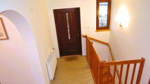 A hallway with a wooden staircase, a radiator, a door, and a framed picture on the wall. - Holiday Home Kolczewo Near Baltic Sea Beach (gmina Wolin)