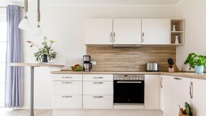 Een moderne keuken met witte kasten, een inbouwoven en een koffiezetapparaat.