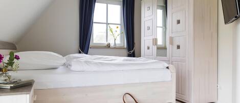 Un dormitorio con cama, armario, escritorio con lámpara y ventana con cortinas.
