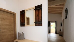 A hallway with wooden flooring, a bench with storage, a large mirror, and a door. - Panorama Apartment Stubai (Neustift Im Stubaital)