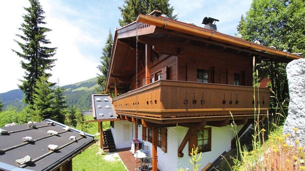 Un chalet en bois doté d’un balcon, d’une terrasse couverte et offrant une vue sur les montagnes environnantes.