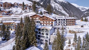 Une station de montagne enneigée, avec plusieurs bâtiments de style chalet, des remontées mécaniques et une vue dégagée sur le paysage enneigé environnant.