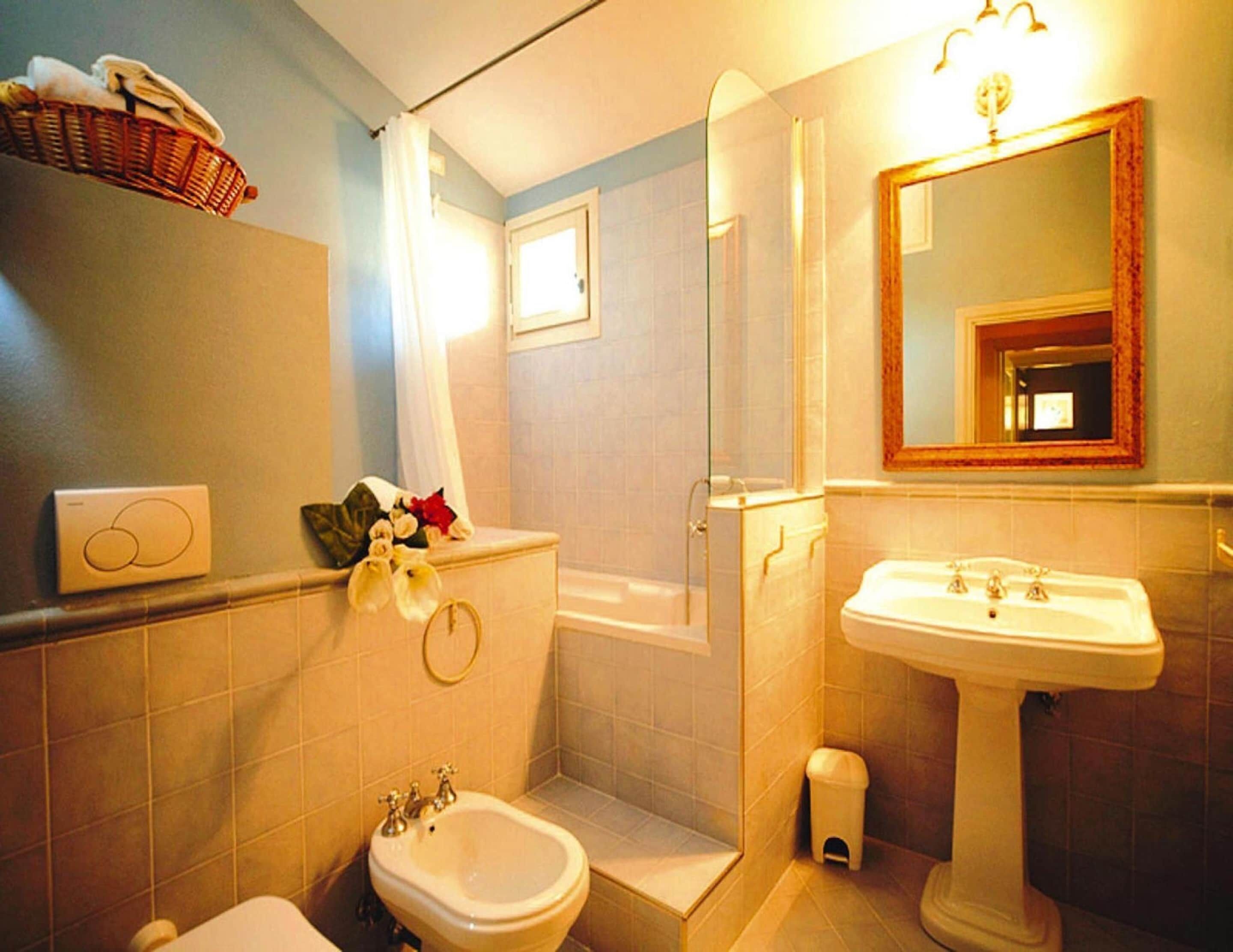 A bathroom with a bidet, a sink, a mirror, and a shower.